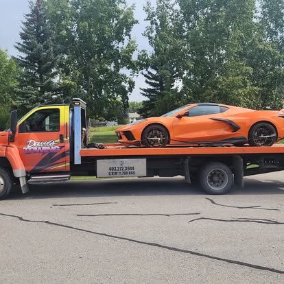 Dave's Towing flatbed truck towing a sports car in High River